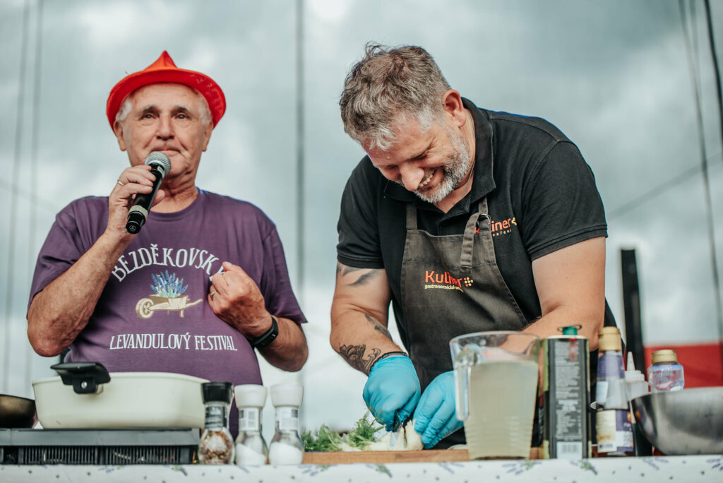 A chef cutting onions on a cutting board with a commentator behind his back