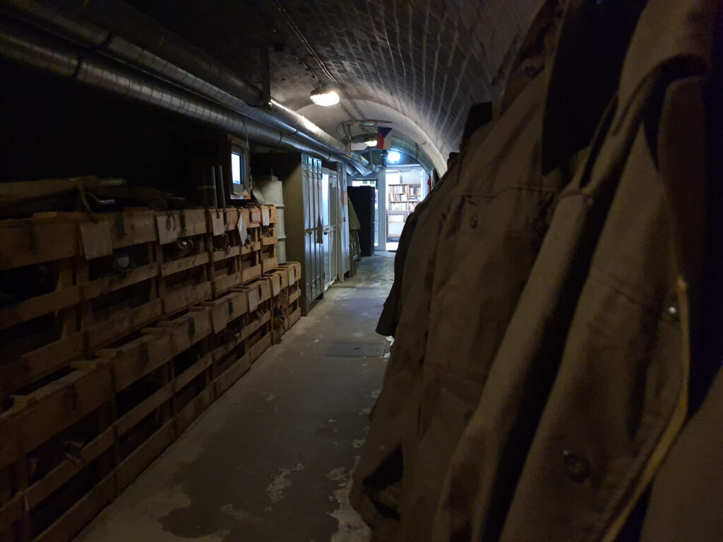 Bunker 10-z area with hanging coats on one side and stacked crates on the other